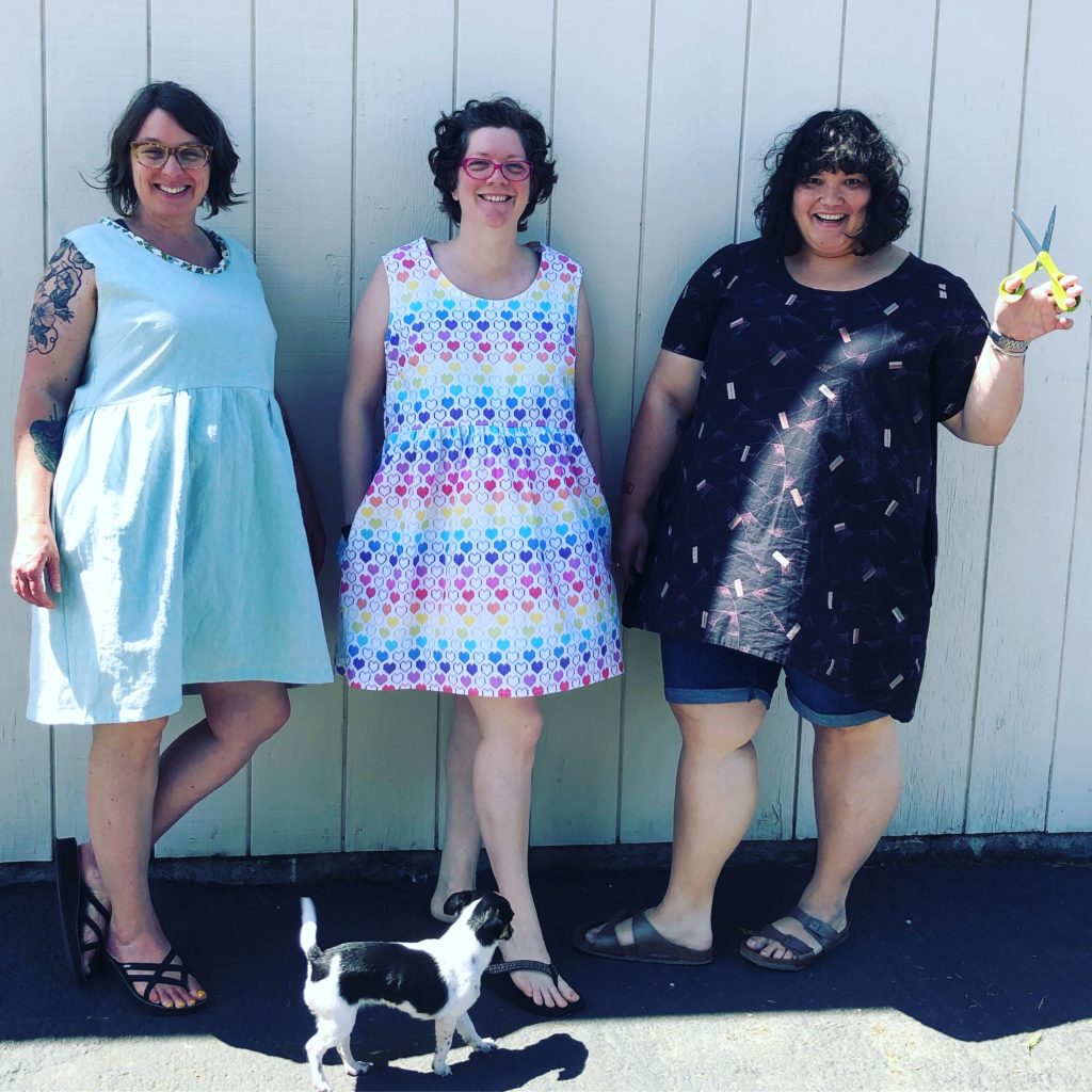 three happy ladies show off what they sewed on a sunny day in early May