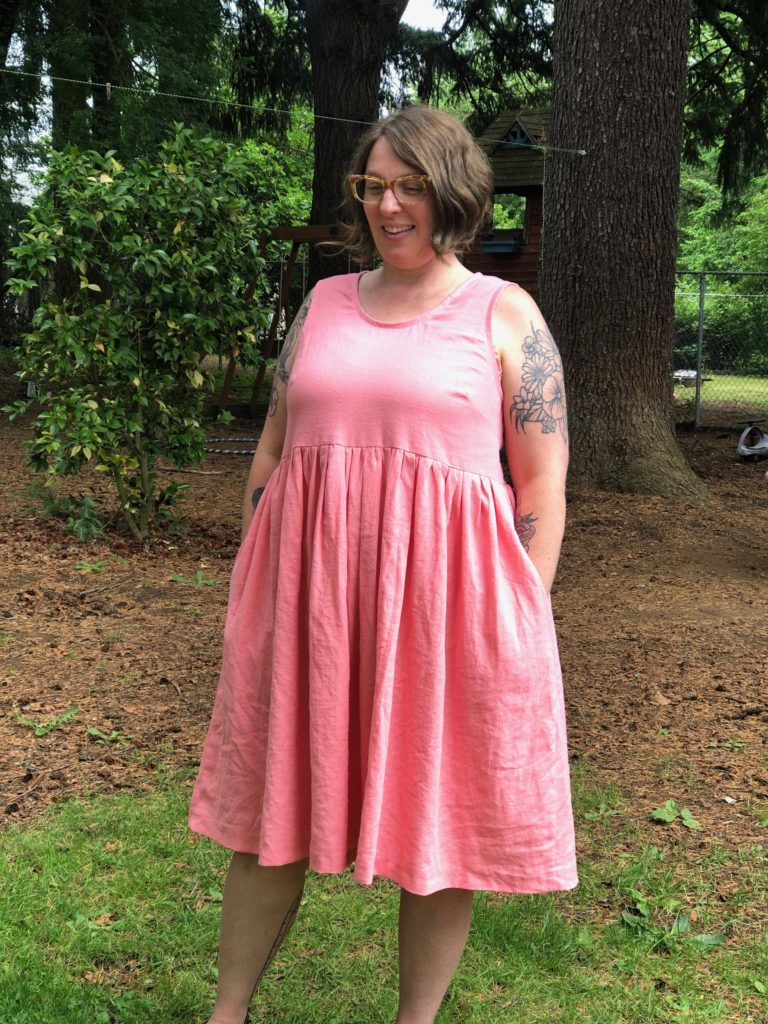 I'm looking at the camera in a pink dress with hands in my pockets